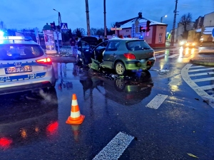Radiowóz policyjny i obok rozbite dwa auta na skrzyżowaniu.