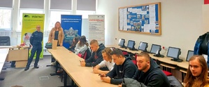 Policjantka i kobieta stojąca przed młodzieżą siedzącą przy stoliku.