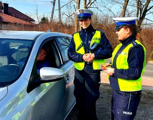 Policjantki stojące przy aucie w którym siedzi uśmiechnięty kierowca.