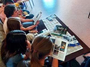 Uczniowie siedzący na kanapach oglądają gazety policyjne na ławie leża ulotki.
