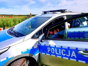 Mały chłopiec  siedzący za kierownicą radiowozu.