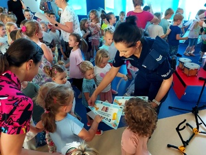 Policjantka w mundurze przekazuje dzieciom dyplomy.