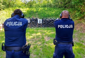 Dwóch policjantów w mundurach mierzy z broni do tarcz.
