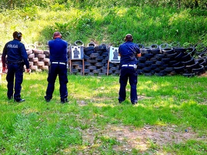 Policjanci ruchu drogowego oraz instruktor przed tarczami do strzelania.