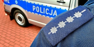 Pagon policjanta z czterema gwiazdkami i radiowóz z napisem policja.
