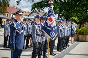 Policjanci stojący w kilku szeregach oraz sztandar.