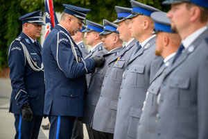 Komendant wręcza brązową odznakę Zasłużony Policjant.