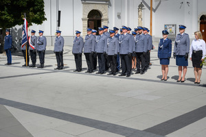 Policjanci stojący w szeregu wraz ze sztandarem.