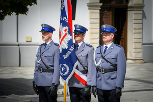 Policjanci stojący ze sztandarem.