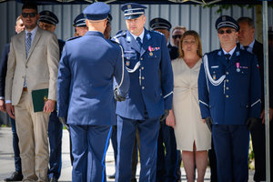 Policjant podaje rękę Komendantowi Wojewódzkiemu w tle inne osoby stojące pod namiotem.