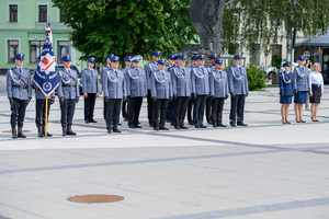 Policjanci stojący w szeregu wraz ze sztandarem.