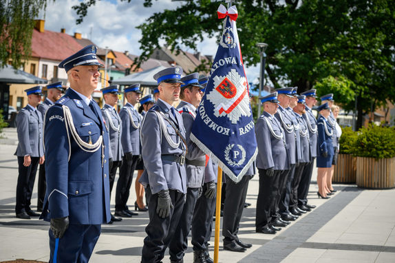 Policjanci stojący na placu oraz sztandar.