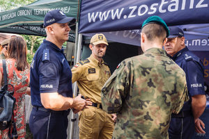 Dwóch policjantów, strażak i żołnierz rozmawiają.