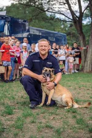 Policjant kuca przy psie służbowym.