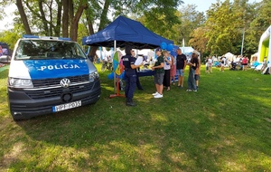 Radiowóz i policjantki przy namiocie grają z dziećmi w koło fortuny.