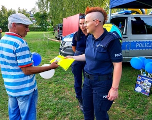 Policjantka przekazuje kamizelkę odblaskowa seniorowi.