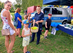 Policjantka częstuje cukierkami z koszyka dziecko.