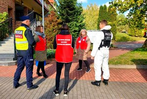 Policjanci rozmawiają z pracownikami sanepidu.