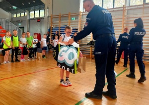 Policjant wręczający nagrodę chłopcu.