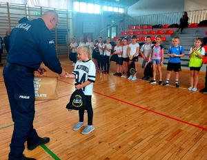 Policjant wręczający nagrodę dziewczynce.