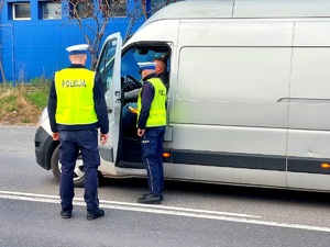 Dwóch policjantów bada stan trzeźwości kierującego busem.