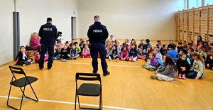 Dwóch policjantów stojących przed dziećmi.