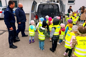 Dwóch policjantów, dzieci oraz radiowóz.