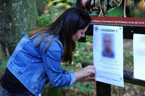Kobieta wieszająca plakat osoby zaginionej