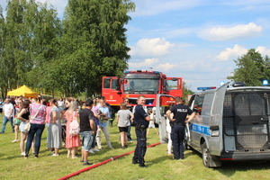 Policjanci, radiowóz policyjny i strażacki oraz uczestnicy spotkania.
