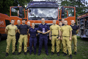 Policjanci i strażacy przy radiowozie.