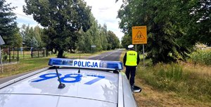 Radiowóz, policjant i znak drogowy.