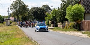 Radiowóz policyjny i osoby jadące na rowerach.