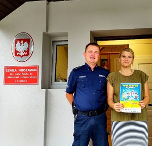 Policjant i nauczycielka z plakatem.
