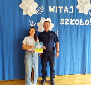 Policjant i nauczycielka z plakatem.