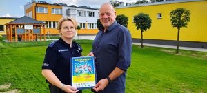 Policjantka z dyrektorem szkoły trzymają plakat.