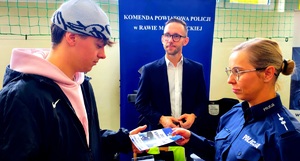 Policjantka wręcza ulotkę uczniowi, za nimi jest pracownik kadr.