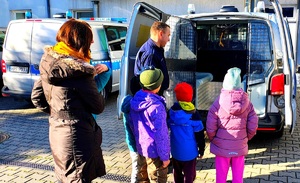 Dzieci patrzące na radiowóz, policjant i nauczycielki.