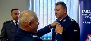 Przewodniczący związku wręcza medal policjantowi.