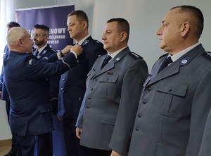 Przewodniczący związku wręcza medal policjantowi.
