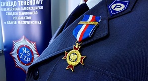 Medal na gabardynie policyjnej w tle napisy dotyczące związku zawodowego.