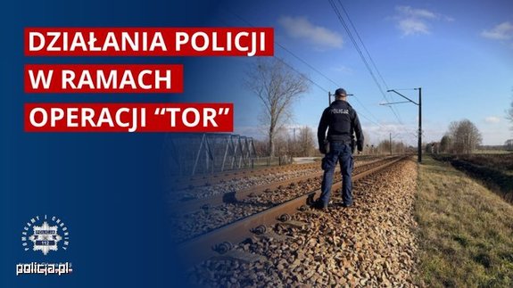 Policjant stojący przy torach oraz napisy.