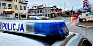 elka na dachu radiowozu z napisem policja i przejście dla pieszych obok budynki.