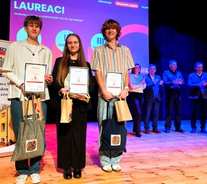 Dwóch chłopców i dziewczyna, wygrani w konkursie oraz w tle organizatorzy konkursu.