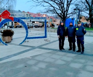 Policjanci oraz strażnik miejski przy sztucznej ozdobie bombki świątecznej.