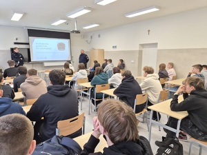 Policjanci przy tablicy i dzieci siedzące w ławkach.