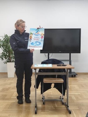 Policjantka z plakatem bezpieczne ferie.