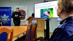 Pracownik NASK i policjantka oraz prezentacja na ekranie.