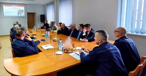 Policjanci oraz samorządowcy siedzący przy stole.