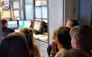 Dzieci zaglądające do pokoju dyżurnego, w którym widać dużo komputerów.