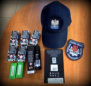 Produkty tytoniowe, czapka policyjna i naszywka z gwiazdą policyjną.